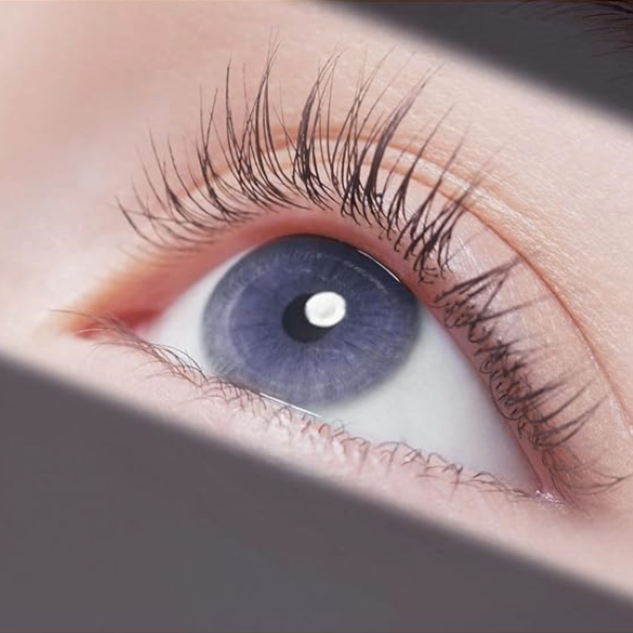 A close-up of a woman's eye with mesmerizing blue eyes and beautifully long eyelashes.