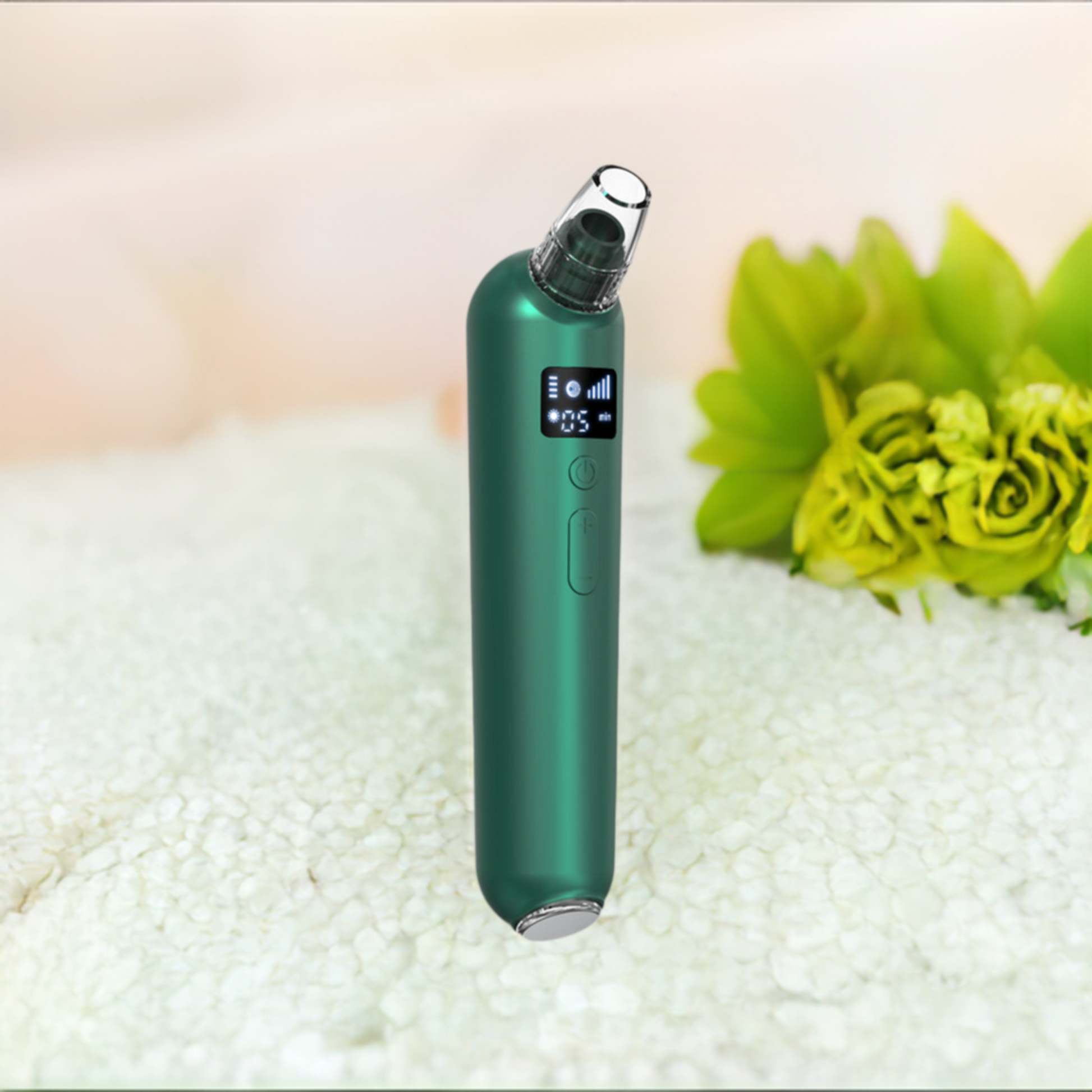 Green electric blackhead remover on a white surface next to a lime green flower.