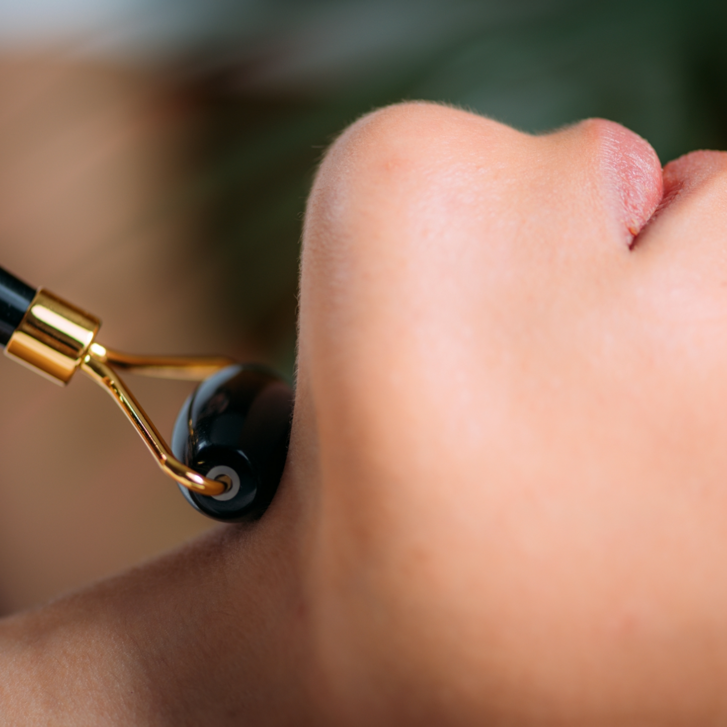 Close up of Premium Obsidian Jade Roller on a woman's neck.